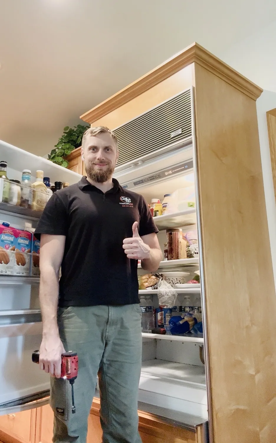 MasterFix technician smiling and giving a thumbs-up beside a refrigerator